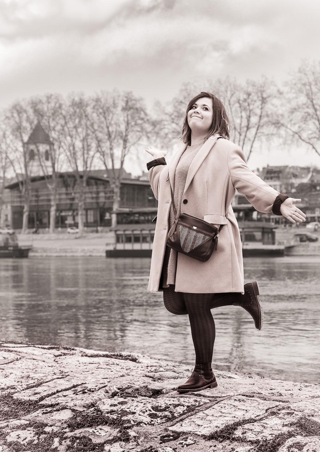 Portrait sépia en bord de Loire d'une jeune femme souriante sur un pied avec les bras écartés